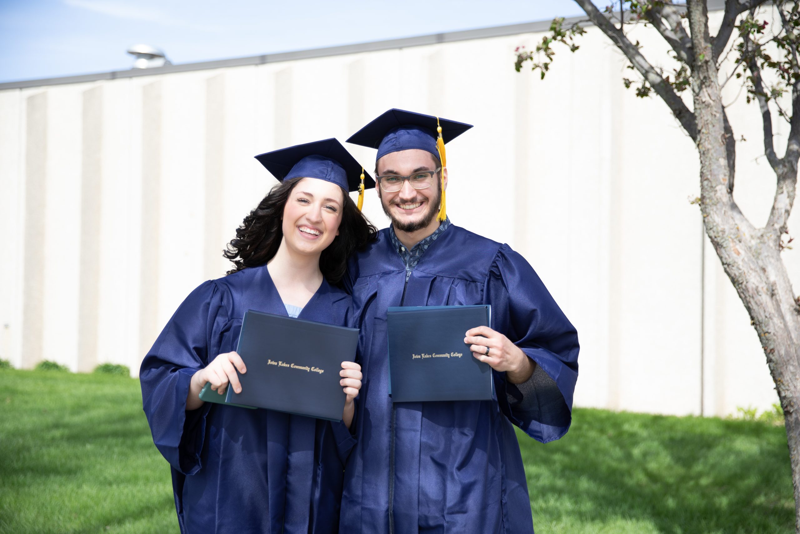 Iowa Lakes students celebrating after graduating, holding their diplomas.